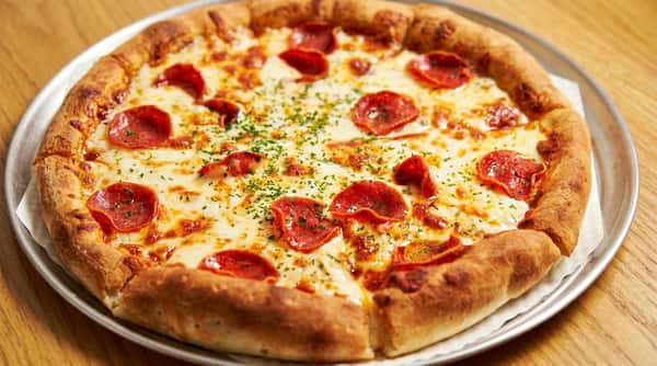 Pepperoni pizza with melted mozzarella cheese and green herb garnish on a metal pan.