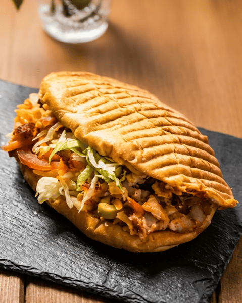 Grilled chicken shawarma panini stuffed with seasoned chicken, lettuce, tomatoes, and fresh vegetables on toasted pressed bread.