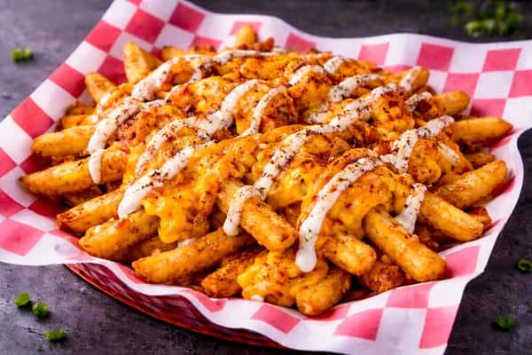 Crispy seasoned French fries smothered in creamy melted cheddar cheese, served in a red checkered basket for classic American comfort food.