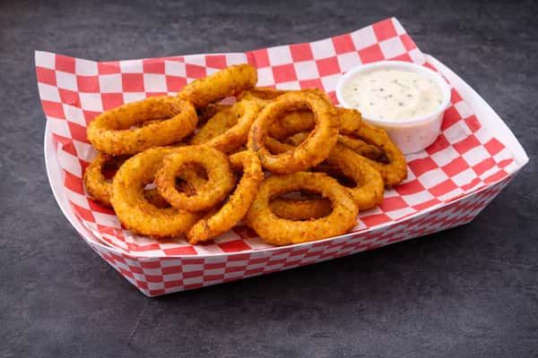 Basket of crispy golden onion rings served with creamy ranch dipping sauce.