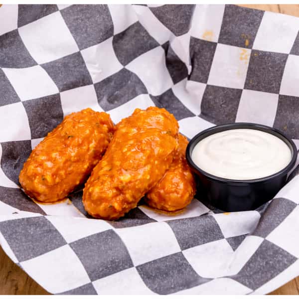 Boneless buffalo chicken wings served with creamy ranch dipping sauce on deli paper.