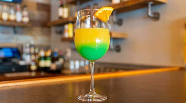 Green tropical cocktail with orange garnish served at Roger's Family Restaurant in Somerset MA