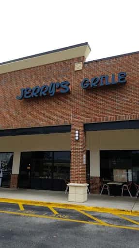 Exterior of Jerry's Grille with brick facade, large black signage, and a few patio tables set near the entrance.