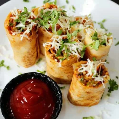 Spring rolls topped with herbs and served with a sauce