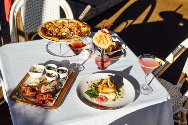 Pizza, charcuterie board, food and drinks on a white tablecloth