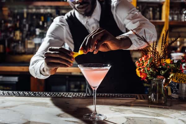 Bartender garnishing a martini with a citrus peel