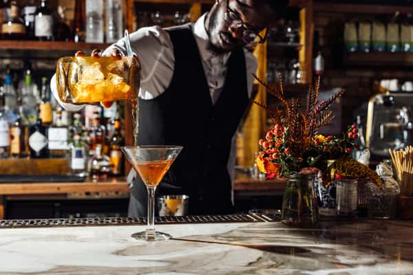 Bartender pouring a cocktail into a glass