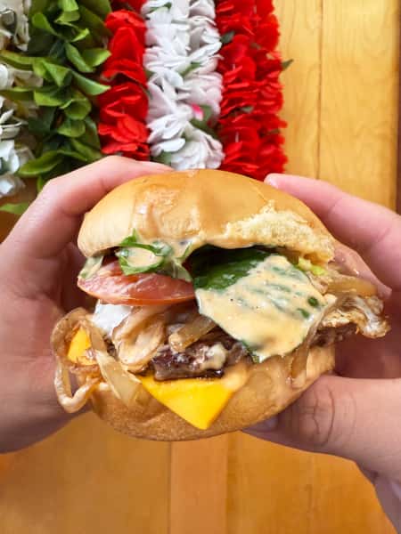 Cheeseburger with lettuce, tomato, grilled onions, egg, and sriracha mayo