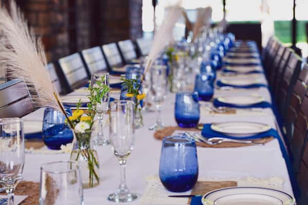 Close-up of a decorated private dinner table at Osteria with pampas grass and blue glasses