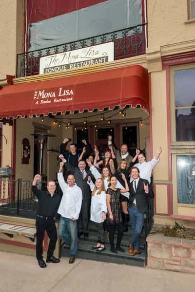 The Mona Lisa Fondue Restaurnat staff waving and standing in front of the building entrance