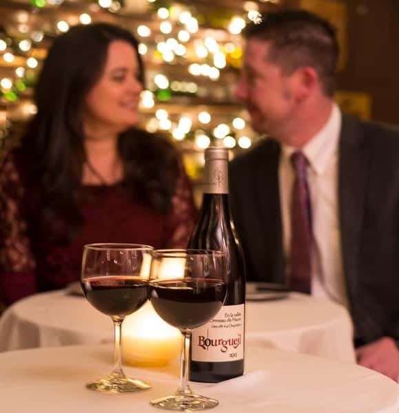 Couple sitting at a candlelit table with wine