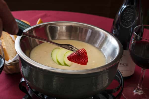 Strawberry about to be dipped into fondue