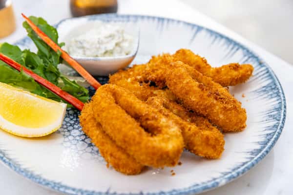 Deliciously crispy fried calamari served with lemon wedge, salad, and dipping sauce.
