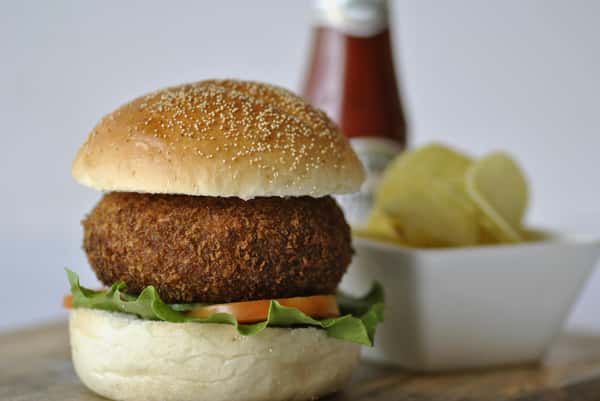 Tasty hamburger with fresh ingredients photographed with chips and ketchup in the background.
