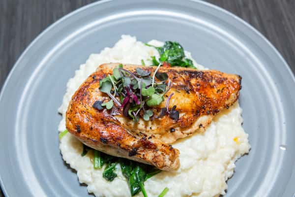 A perfectly seared salmon fillet glazed with a rich, caramelized sauce sits over creamy mashed potatoes, finished with fresh herbs for a vibrant and refined presentation.