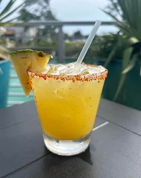 Pineapple margarita with chili rim and foam topping, tropical Mexican cocktail on outdoor patio