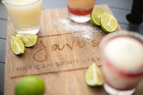 Assorted margaritas with lime wedges and salt on branded wooden board, Mexican restaurant drink display