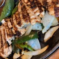 Grilled chicken fajitas with charred peppers and onions, sizzling skillet-style Mexican entrée