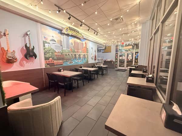 Interior view of Downtown Capriccio's restaurant featuring a city skyline mural, wall-mounted electric guitars, and decorative string lights.