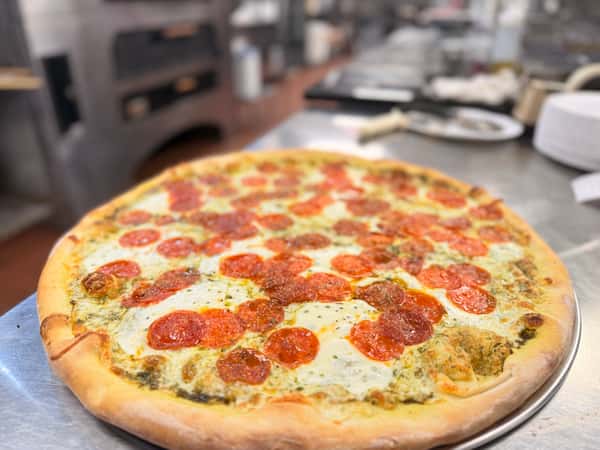 Freshly baked pepperoni pizza with melted mozzarella cheese and a golden-brown crust on a stainless steel kitchen counter.
