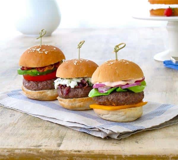 three hamburger sliders with cheese, lettuce and tomatoes