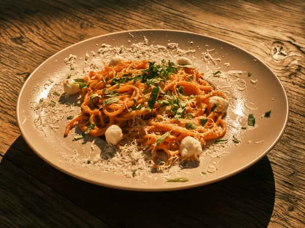 Plate of spaghetti with tomato sauce, garnished with grated cheese, parsley, and small dollops of creamy white sauce.