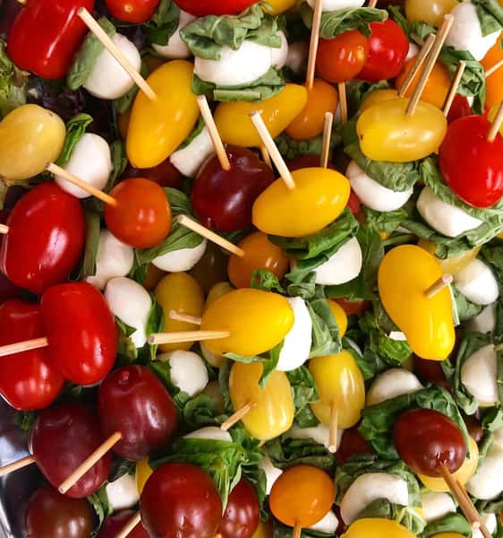 Caprese skewers with cherry tomatoes, mozzarella, and basil.