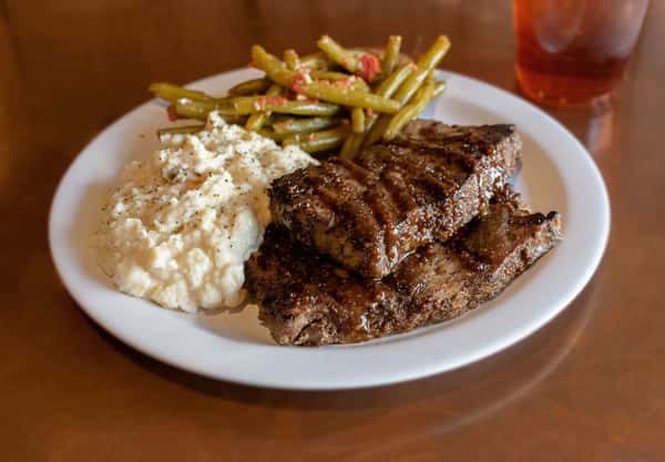 Grilled steak with mashed potatoes and green beans.