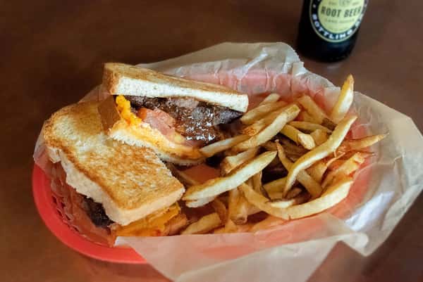 Patty melt with fries served in a diner basket.