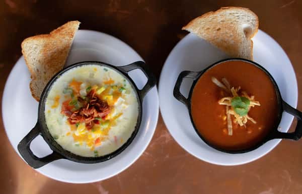 Two bowls of soup served with toasted bread slices.