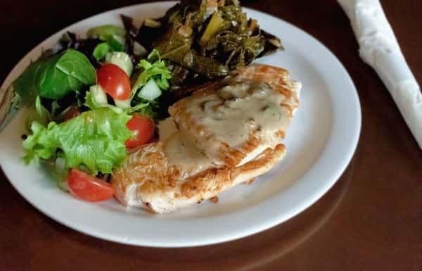 Grilled chicken with creamy herb sauce, served with collard greens and a side salad.