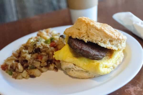 Sausage and egg biscuit sandwich with sides.