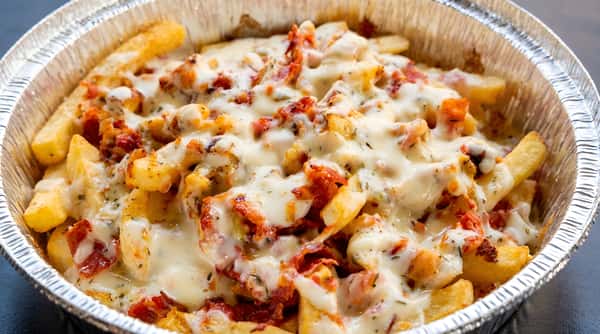 Loaded french fries with melted white cheese and crumbled bacon in a foil container.