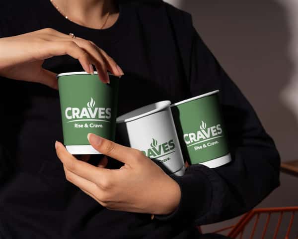 Person holding three hot coffee cups with the Craves logo