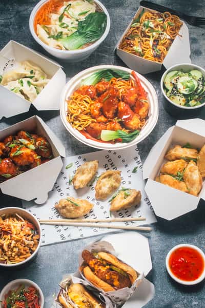 Overhead shot of food boxes with dumplings, noodles and sides