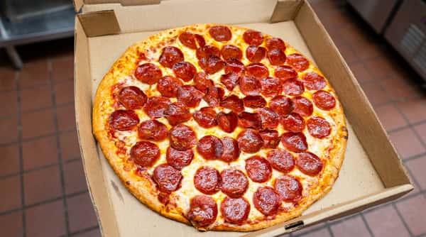 Pepperoni pizza in an open cardboard box, with melted mozzarella and a golden crust.