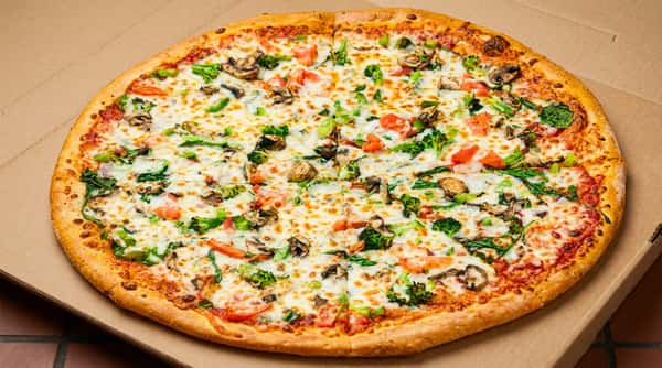 Large pizza with melted cheese, broccoli, mushrooms, small red pieces, and green herbs in a cardboard box.