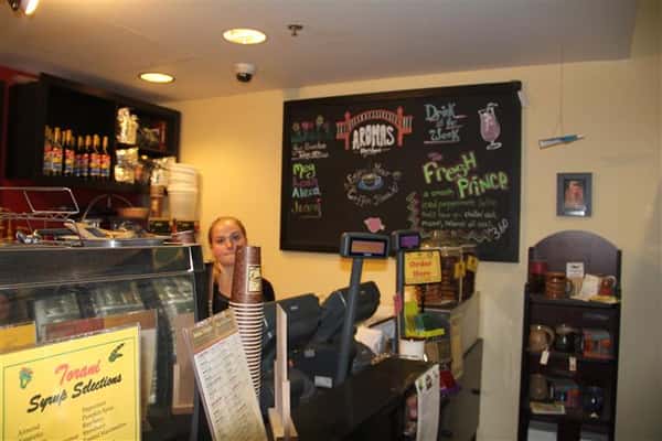 worker behind counter with menu on chalkboard
