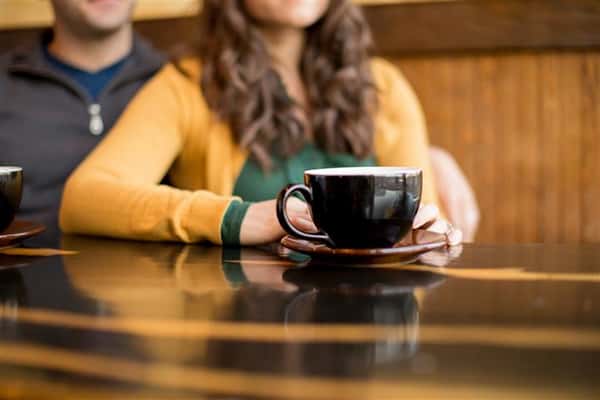 coffee cup on table with a male and female sitting in the background