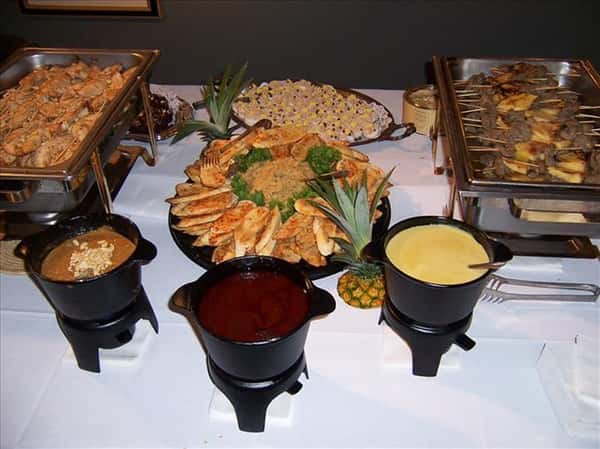 buffet table with trays and a variety of food items with sauce