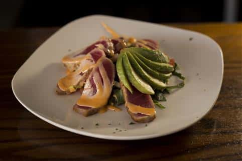Plate of the Seared Tuna served with avocado slices and honey sriracha aioli.
