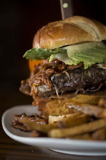 Close up of cheese burger with caramelized onions, lettuce, and tomato.