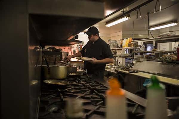 Chef in the kitchen standing in front of the grill.