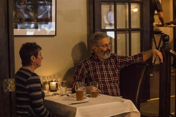 Man and woman sitting at a table set for two against the wall.