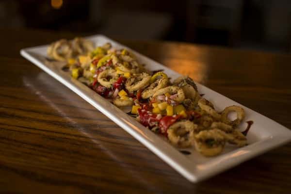Plate of fried Calamari tossed with roasted red peppers, banana peppers, topped with mango salsa & a balsamic drizzle.