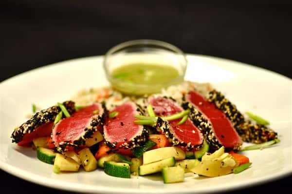 Ahi tuna with a side of rice and mixed vegetables served with a dressing on the side.
