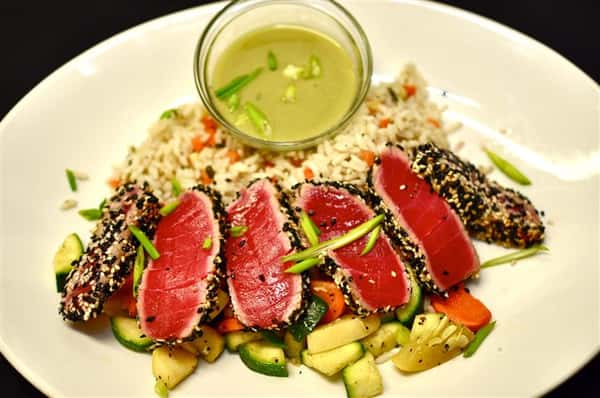 Ahi tuna with a side of rice and mixed vegetables served with a dressing on the side.
