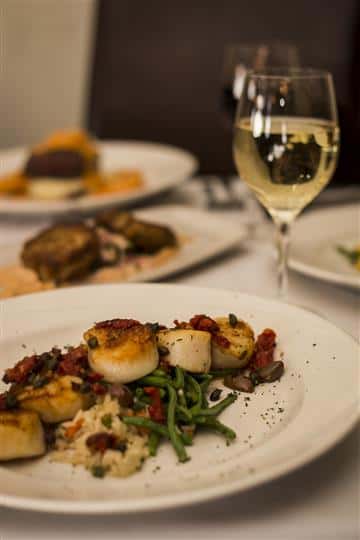 Pan Seared Scallops with sundried tomatoes, garlic, capers, basil and kalamata olives served with rice pilaf with a glass of white wine.