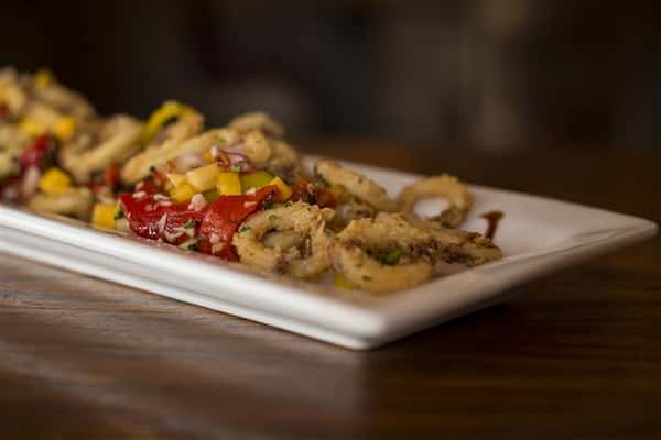 Plate of fried Calamari tossed with roasted red peppers, banana peppers, topped with mango salsa & a balsamic drizzle.