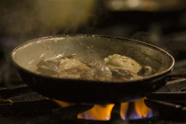 Food in a white cream sauce being cooked in a skillet.